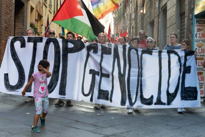 Difesa dei diritti palestinesi durante una manifestazione in centro ad Arezzo, con bandiere e un grande striscione captionato 