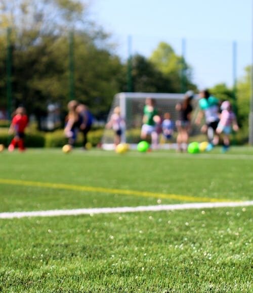 Giovani e sport: bambini che giocano a calcio in un campo all'aperto.